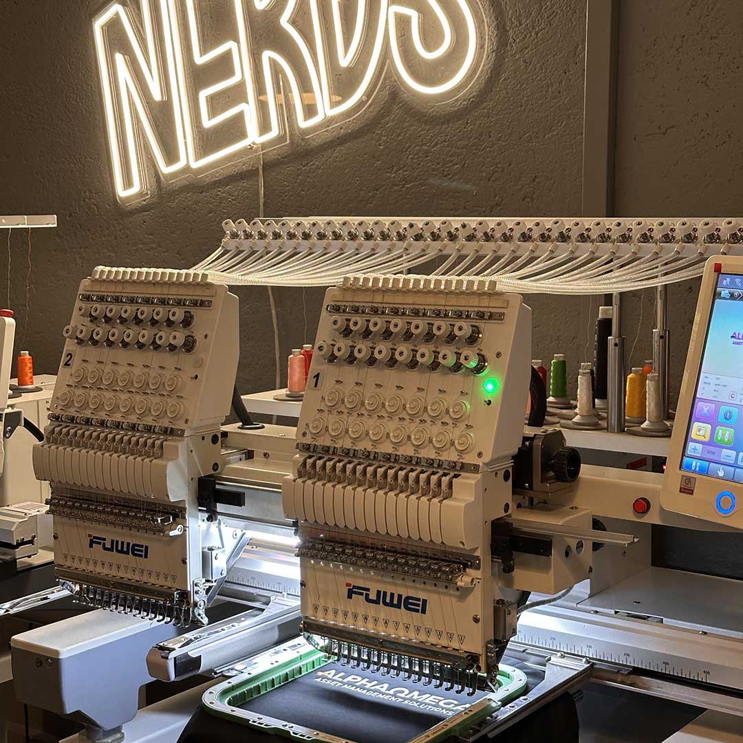 Embroidery machine with 'FUWEI' branding under a neon sign reading 'NERD'.