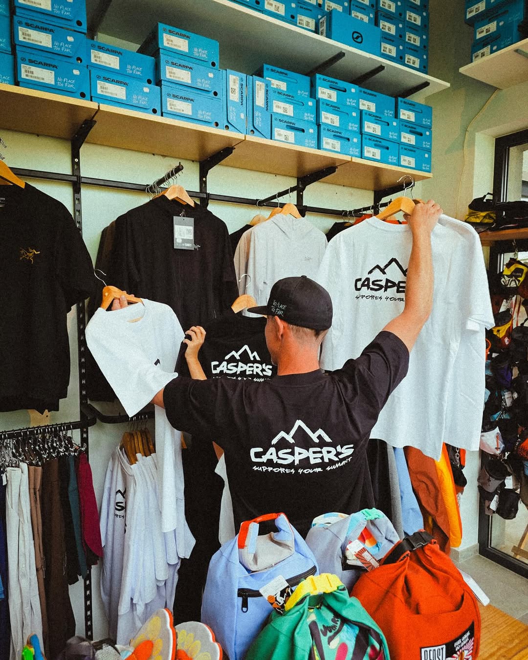Person wearing a screen printed Casper's shirt in a store with shelves of shoes and clothing.